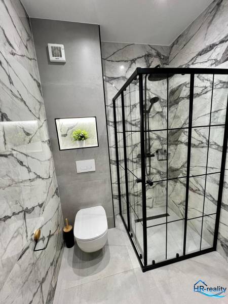 A nyaraló apartman fürdőszobája WC-vel, zuhanyzóval és márványburkolattal.
