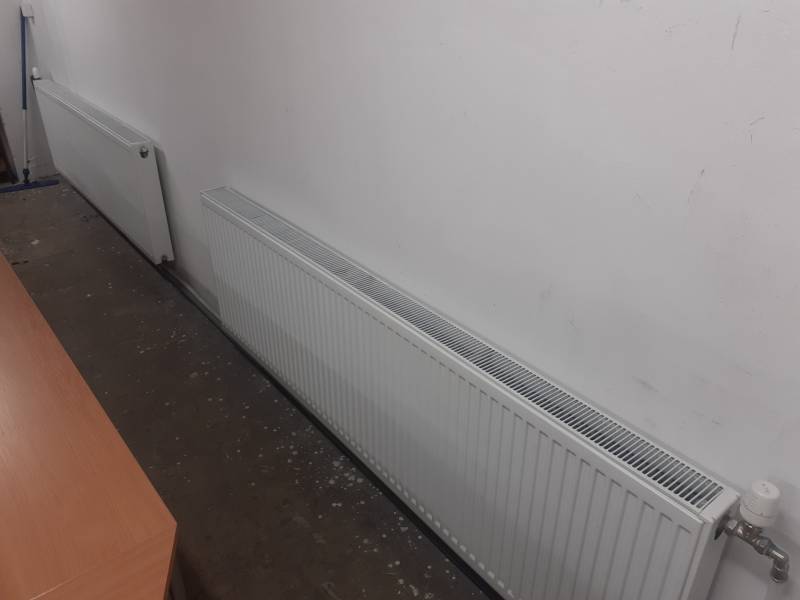 Radiátorok a raktárban és a csarnokban, a falnál betonpadlóval.