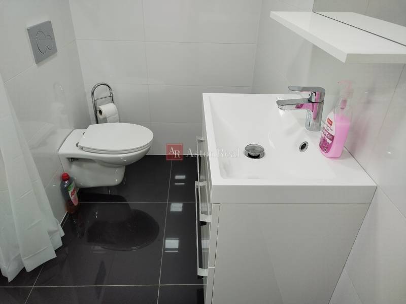 Fürdőszoba családi házban WC-vel, mosdóval és fehér csempékkel.