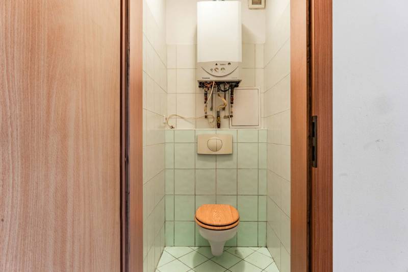 Fürdőszoba WC-vel és bojlerrel egy kétszobás lakásban, csempével burkolva.