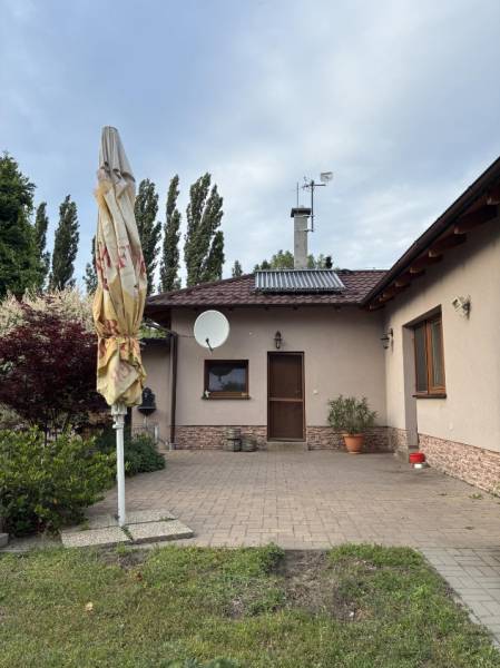 Családi ház Malackán, előkert terasszal, zölddel és műholdas antennával.