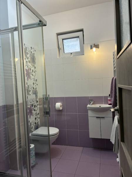 Fürdőszoba csempékkel családi házban, zuhanyzó, mosdó, WC.