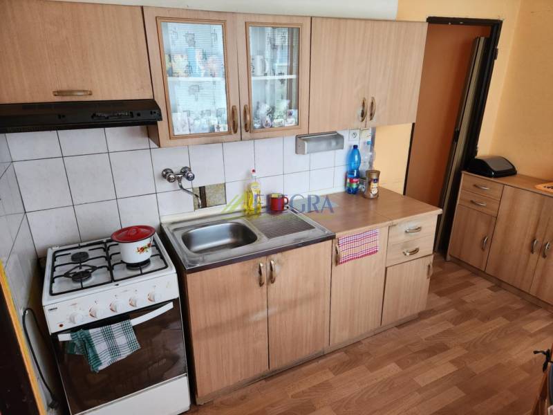 Konyha egy egyszobás lakásban fa szekrényekkel és gáz tűzhellyel.