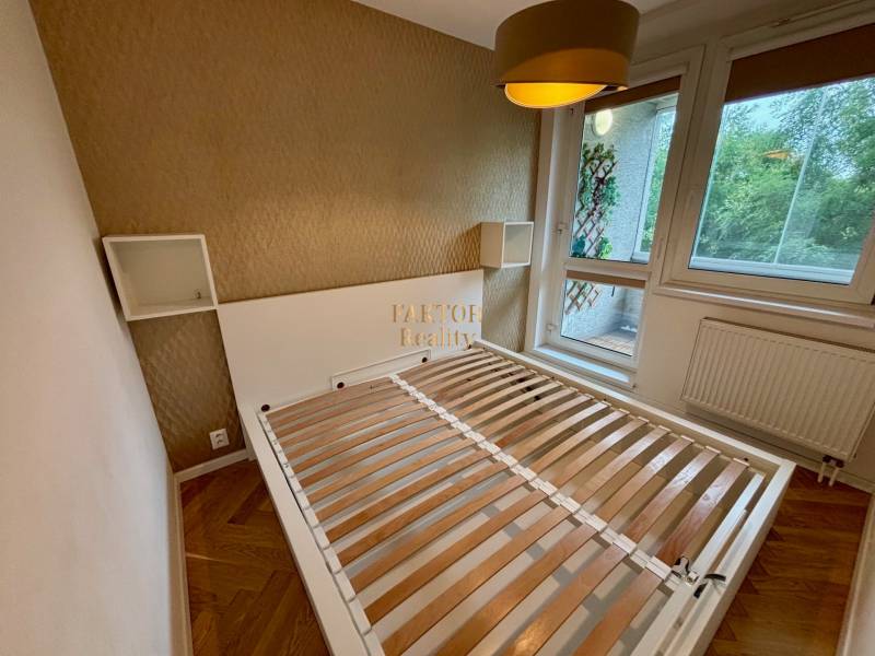 Hálószoba egy kétszobás lakásban ággyal, tapétával, ablakkal és francia erkéllyel.