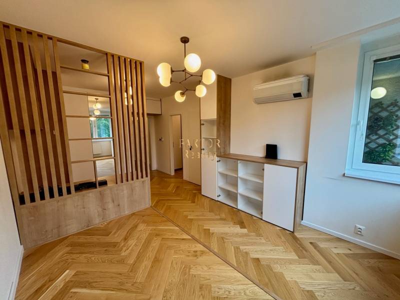 2 szobás lakás belső tere fa padlóval, válaszfallal és modern világítással.