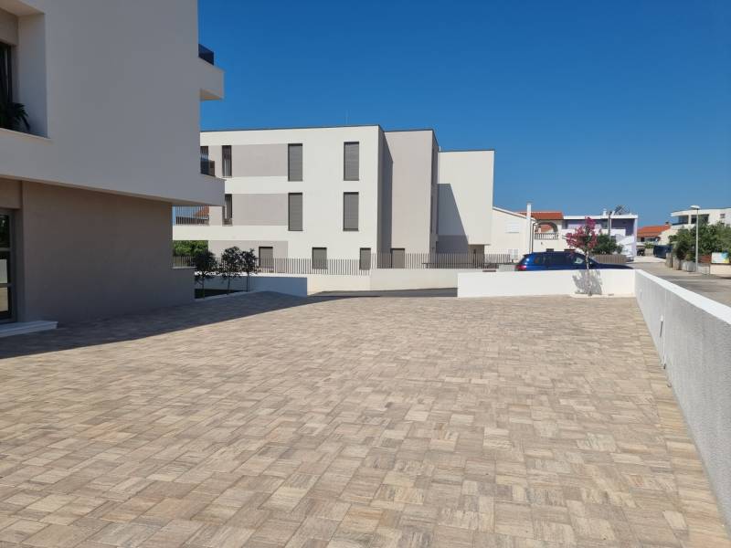 Négy szobás lakás parkolója Vodice városában szilárd burkolattal és tiszta építészettel.