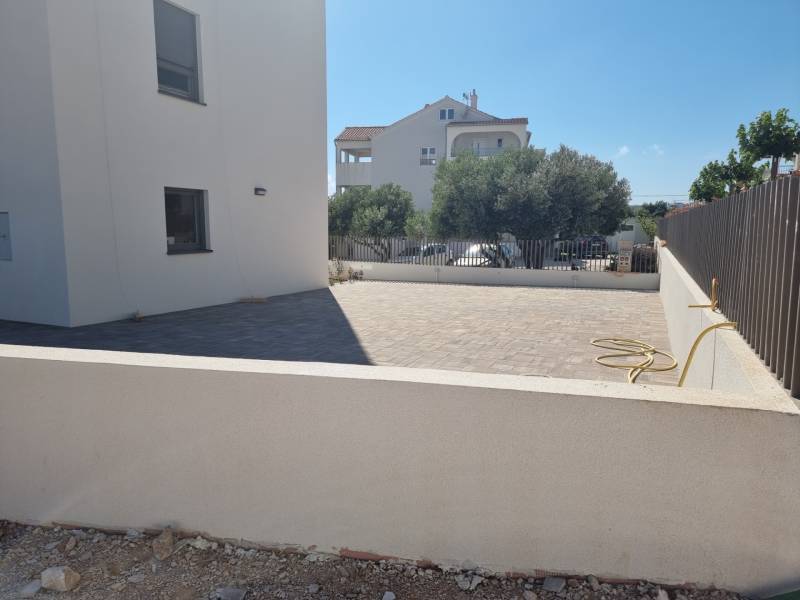 Udvar egy 4 szobás lakásnál Vodice-ben, burkolt terasszal és alacsony kerítéssel.
