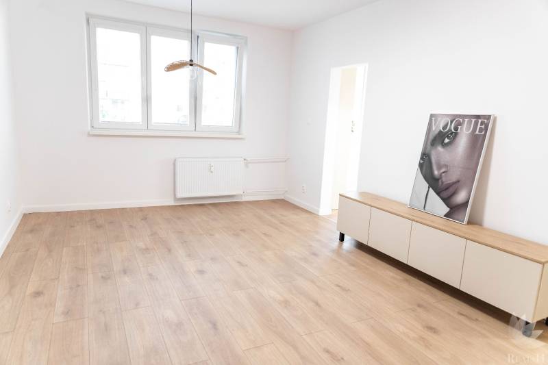 Világos szoba egy kétszobás lakásban fa padlóval és dekorációval.