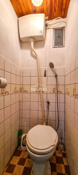 Kis fürdőszoba a házikóban WC-vel, csempékkel és fa mennyezettel.