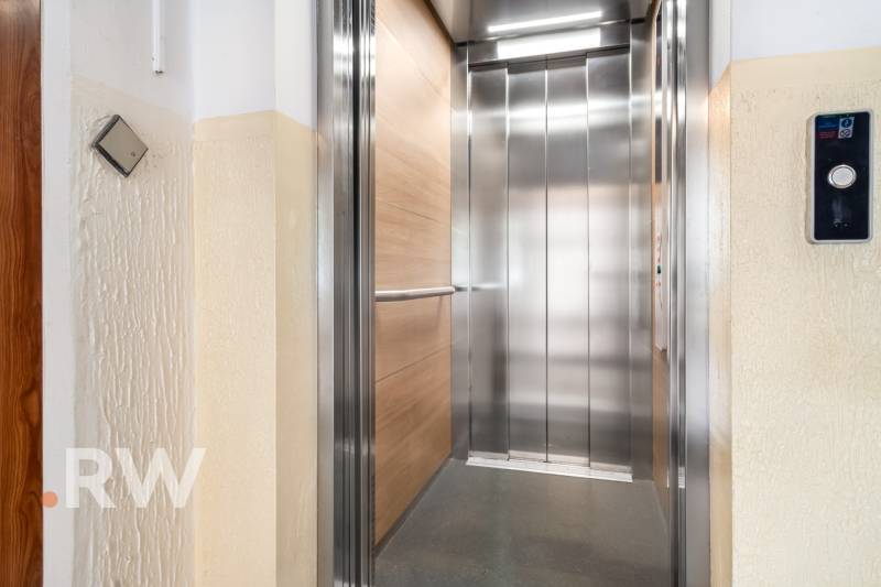 Modern lift kinyitása egy lakóház emeletén fa dekorációval.