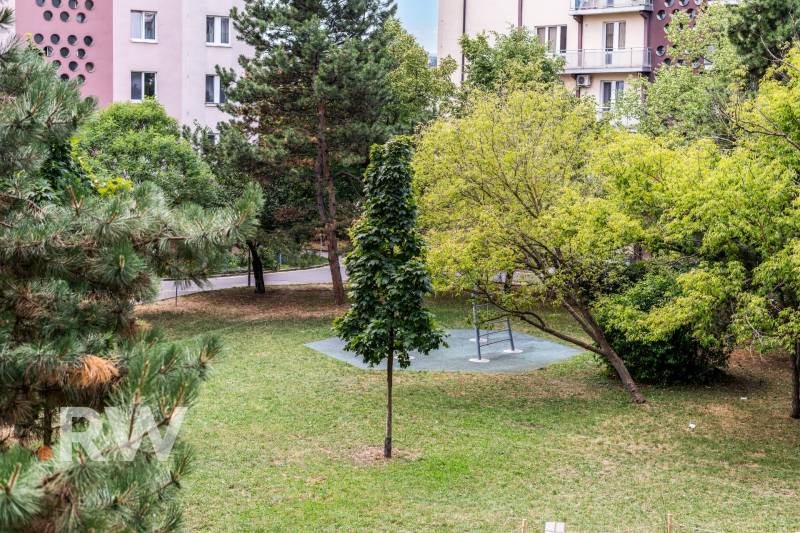 Pozsonyban, a Csehszlovák Ejtőernyősök parkja, padokkal és zöldterülettel, lakóházakkal körülvéve.
