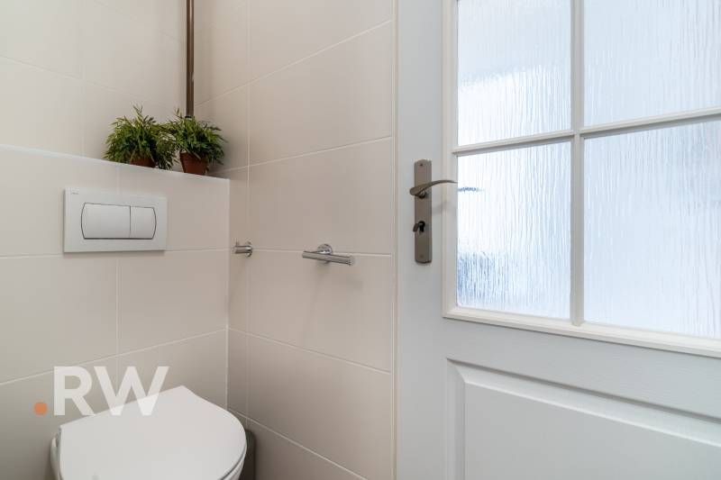 Kétszobás lakás fürdőszobája WC-vel, kerámia burkolattal és üvegajtókkal.