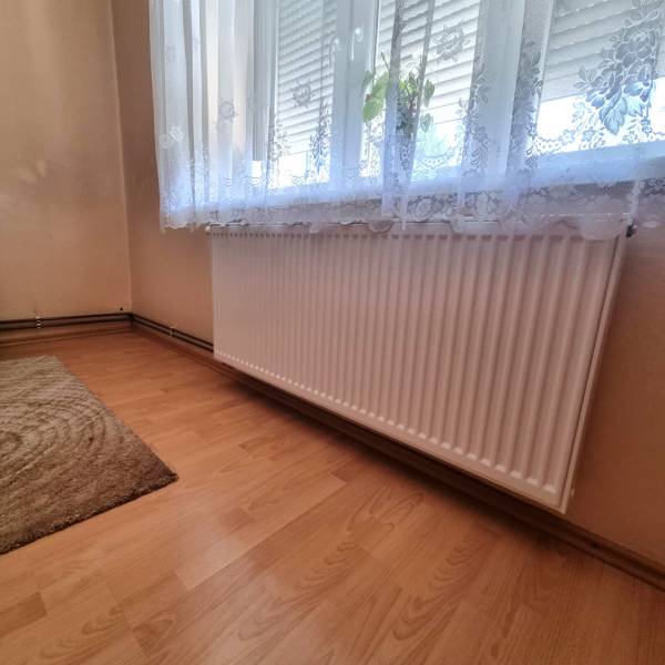 Szoba radiátorral az ablak alatt és függönnyel a családi házban.