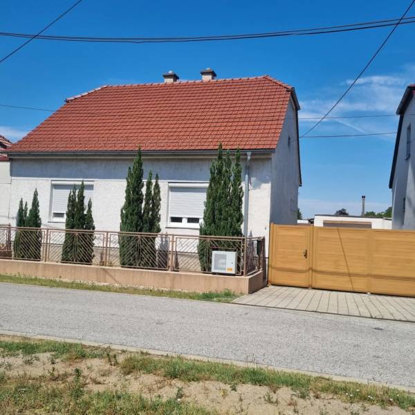 Családi ház a Písniky utcában, Malackán, fehér homlokzat, piros tető, tujafák a kerítésnél.