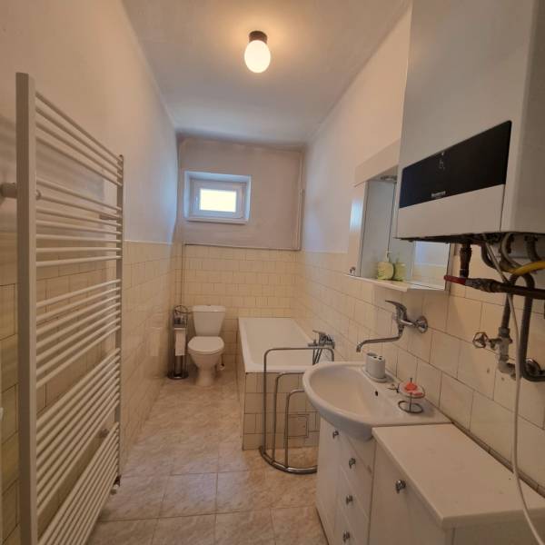 Fürdőszoba családi házban káddal, WC-vel és mosdóval világos árnyalatokban.