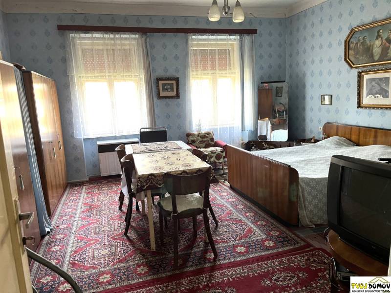 Hálószoba családi házban, fa bútorokkal, szőnyeggel és faldekorációkkal.