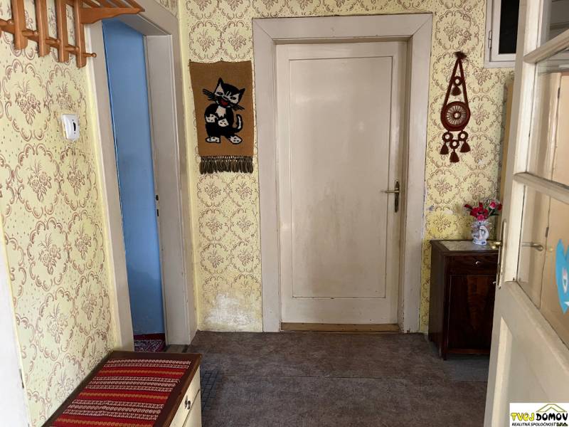 Folyosó egy családi házban tapétákkal, fa bútorokkal és dekorációkkal a falakon.