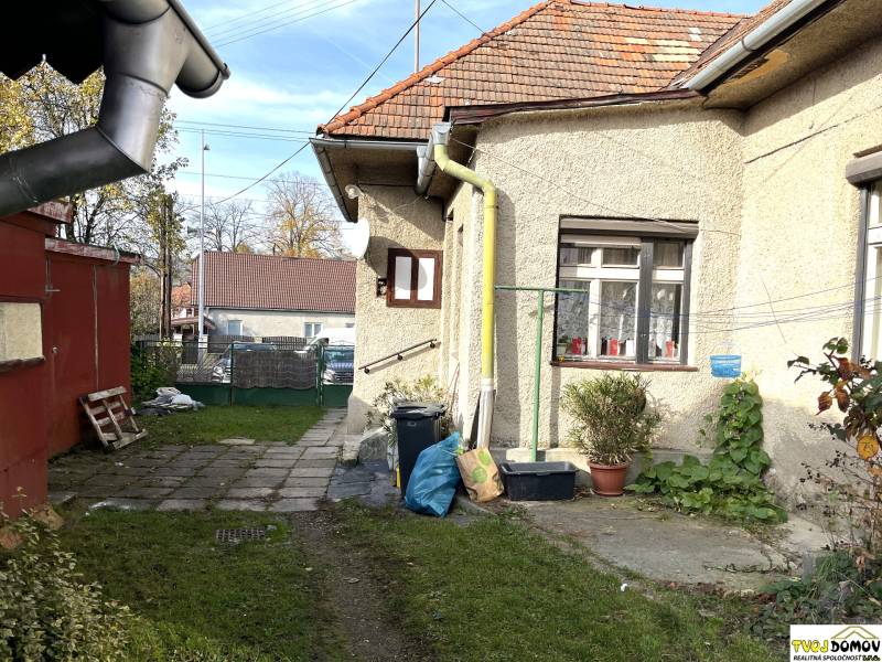 Családi ház a Partizánska utcában, Detván, udvarral, növényekkel és vízelvezető csövekkel.