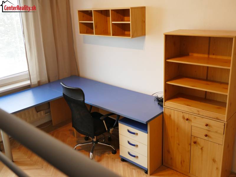 Otthoni iroda kék asztallal és fa tárolóbútorral egy háromszobás lakásban.