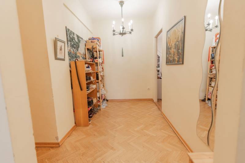 Egy 4 szobás lakás folyosója cipőtartó polcokkal és fa dekorációs padlóval.