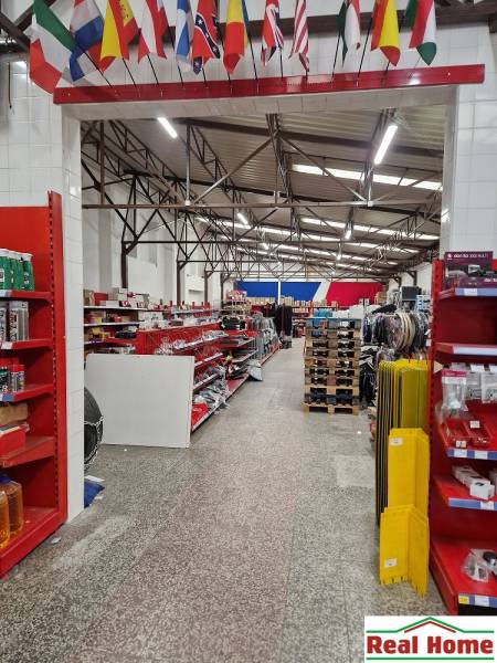 Az üzlet a Somorjai úton különféle árukat kínál a raktárak és csarnokok között, felakasztott zászlókkal.