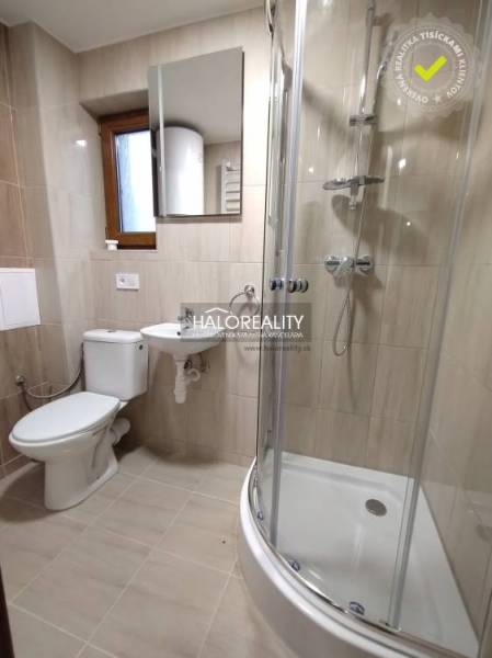 Fürdőszoba a garzonlakásban WC-vel, mosdóval és zuhanyzóval.