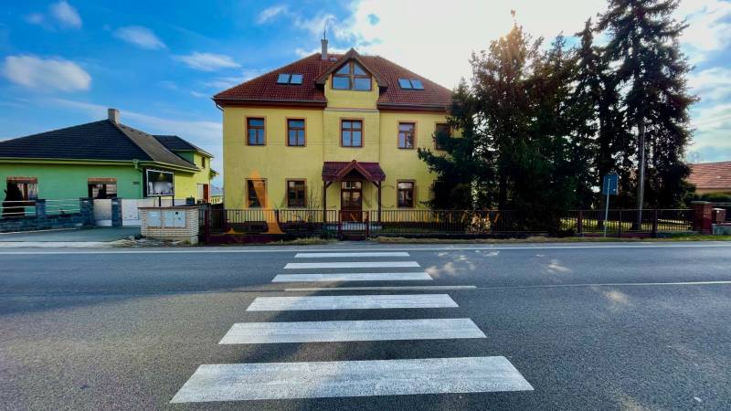 Az épület a Chrabrany utcában, Topoľčanyban, a gyalogátkelőhellyel és a fákkal szemben.
