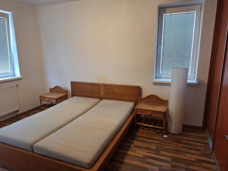 Hálószoba egy kétszobás lakásban fa ággyal és éjjeliszekrényekkel.