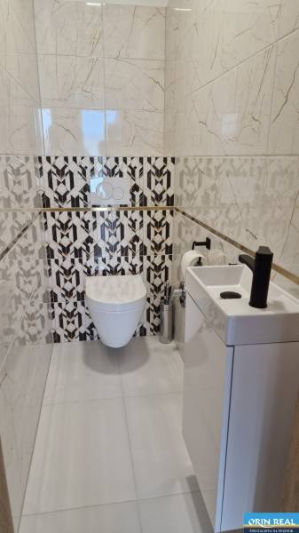 Fürdőszoba WC-vel, modern csempékkel és tágas mosdókagylóval egy kétszobás lakásban.