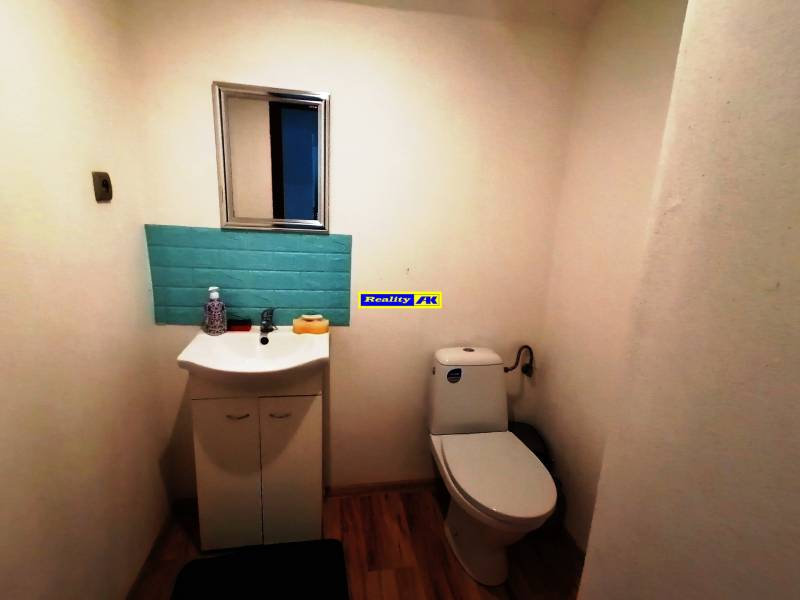 WC egy családi házban mosdóval, tükörrel és kék csempével.