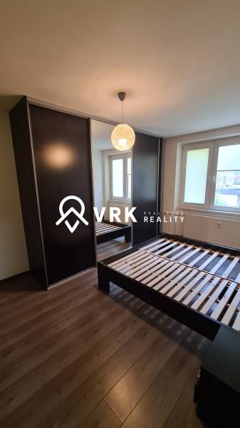 Hálószoba egy kétszobás lakásban sötét gardróbbal, ággyal és ablakkal.