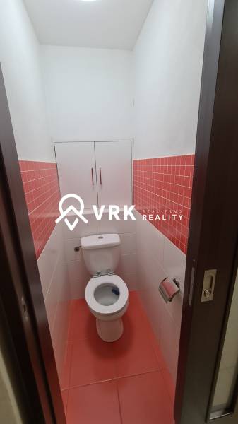 Fehér csempével burkolt fürdőszoba és szekrény a kétszobás lakásban piros csempékkel.