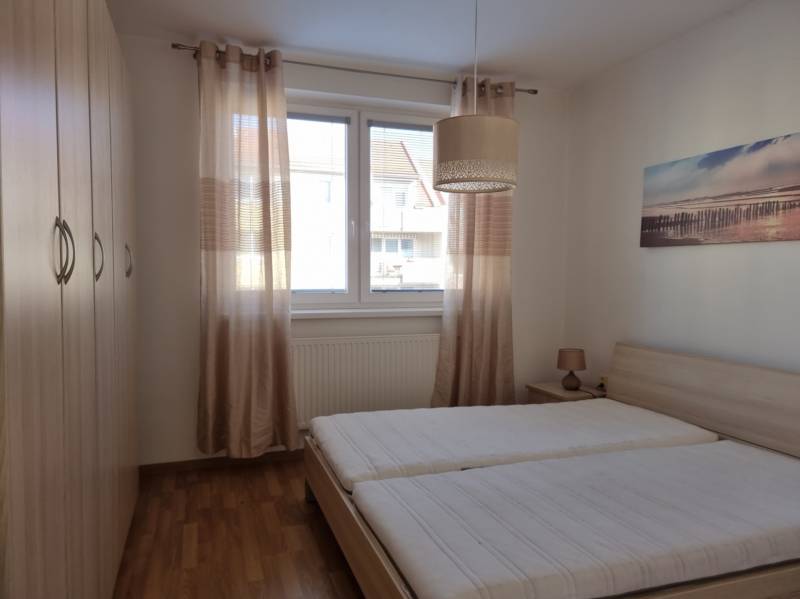 Hálószoba két ággyal, beépített szekrénnyel és képpel egy kétszobás lakásban.