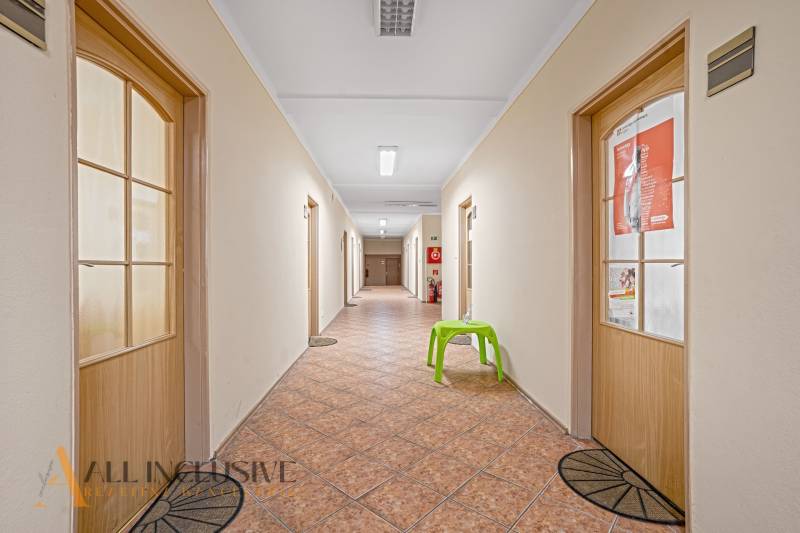 Folyosó ajtókkal, csempével és zöld székkel az irodákban.