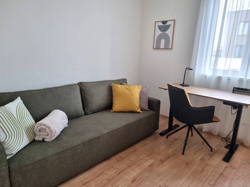 Nappali egy háromszobás lakásban kanapéval, íróasztallal és székkel.