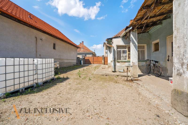 Családi ház udvara Jahodnán kerékpárral és nagy víztartályokkal.