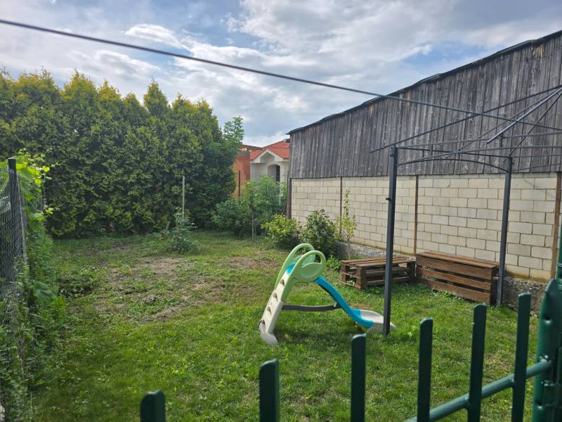 Egy 4 szobás lakás kertje Kocovce-ban hintával és zöld növényzettel.
