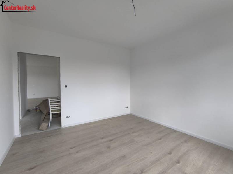 Üres szoba fehér falakkal és világos fa padlóval egy családi házban.