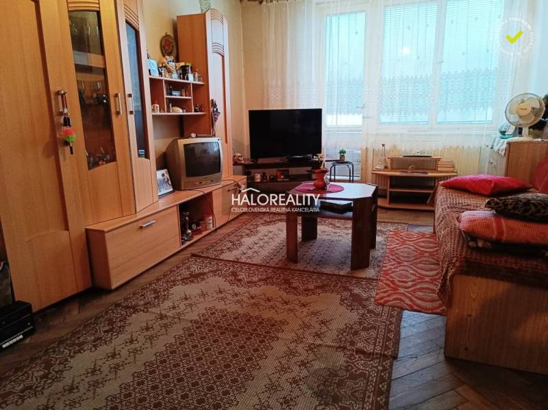 Nappali egy kétszobás lakásban alapvető berendezéssel és szőnyeggel a padlón.