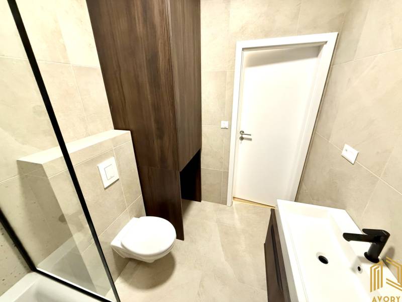 Fürdőszoba a garzonlakásban függesztett WC-vel és modern mosdóval.