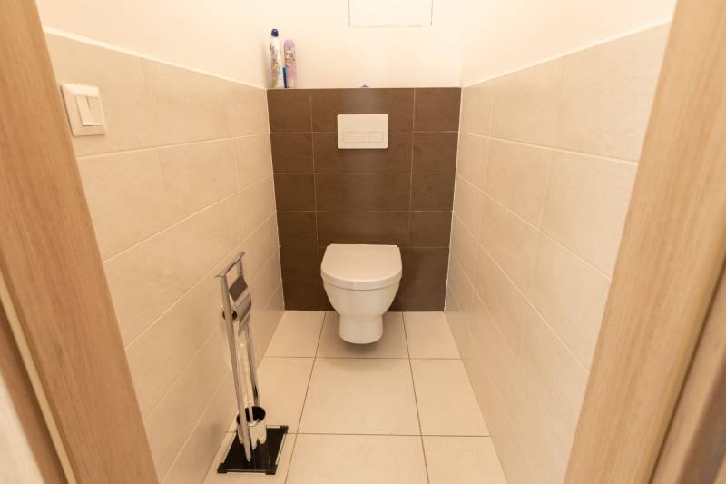 Különálló WC egy háromszobás lakásban csempével és szaniterekkel.