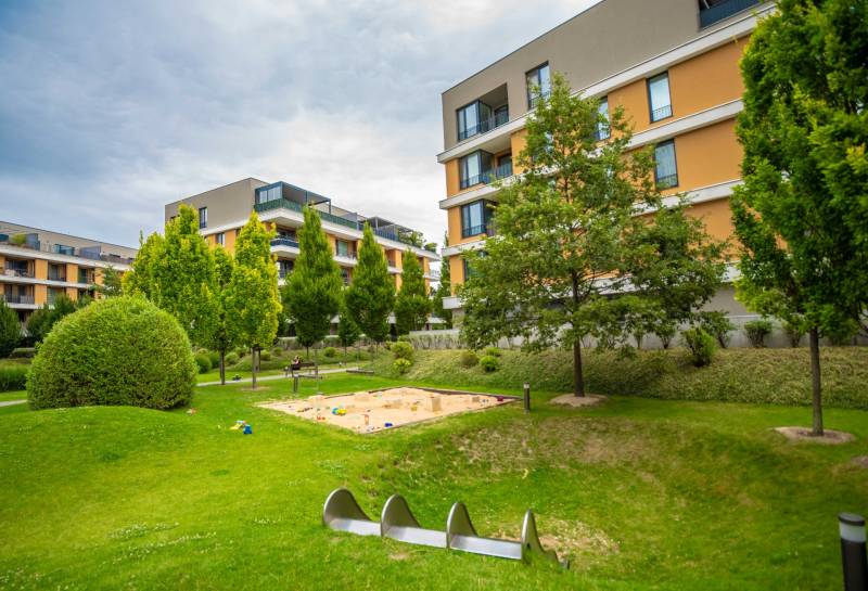 Több lakóépületből álló terület, játszótér és rendezett zöldterület Pozsony-Ružinovban, Bajkalská.