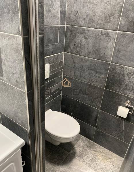 Fürdőszoba egy négy szobás lakásban sötétszürke csempékkel és WC-vel.