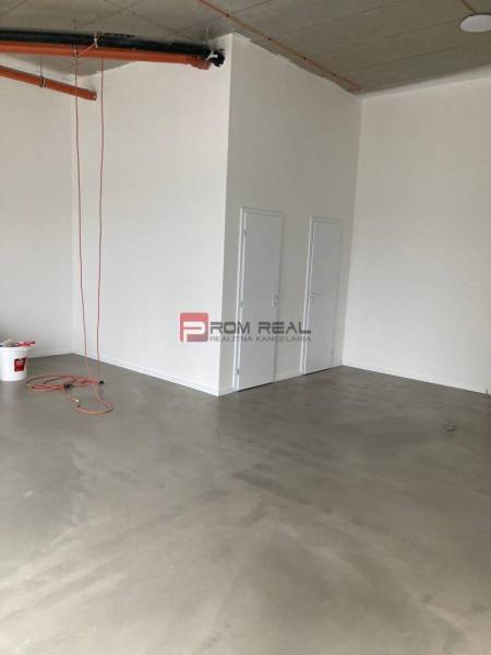 Üres helyiség betonpadlóval és ajtóval az üzlethelyiségben.