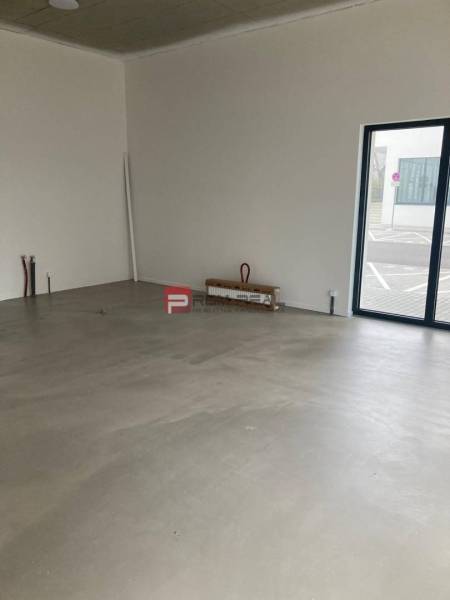 Üzlethelyiségek nagy ablakokkal és betonpadlóval.