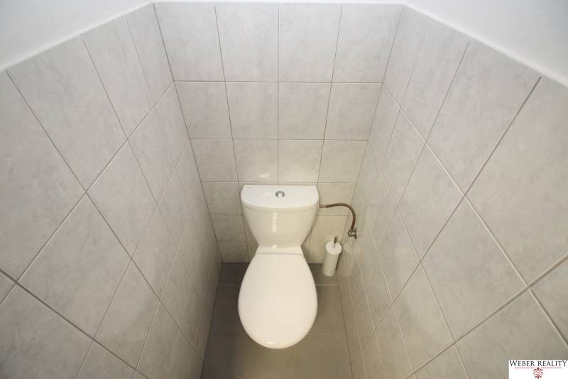 Fehér csempével burkolt WC üzlethelyiségben.