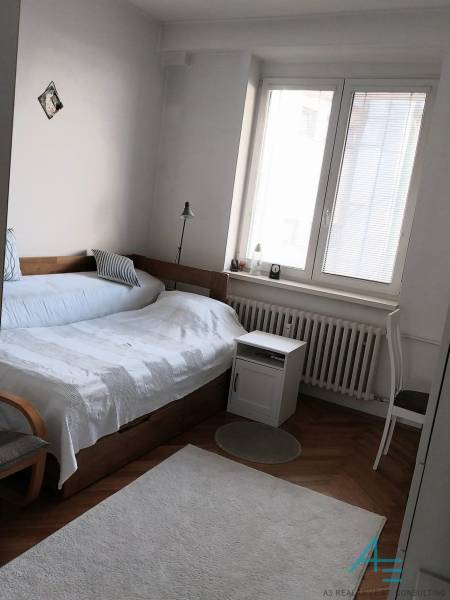 Hálószoba ággyal, lámpával és ablakkal egy 4 szobás lakásban.