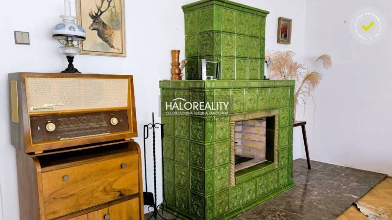 Zöld cserépkályha, vintage rádió és dekorációk egy családi ház belső terében.