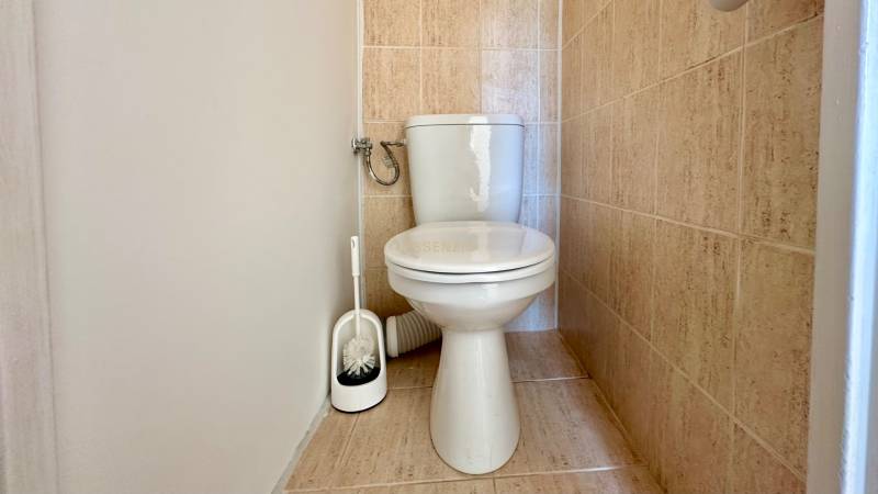 Fehér csészével és csempével ellátott WC egy háromszobás lakásban.