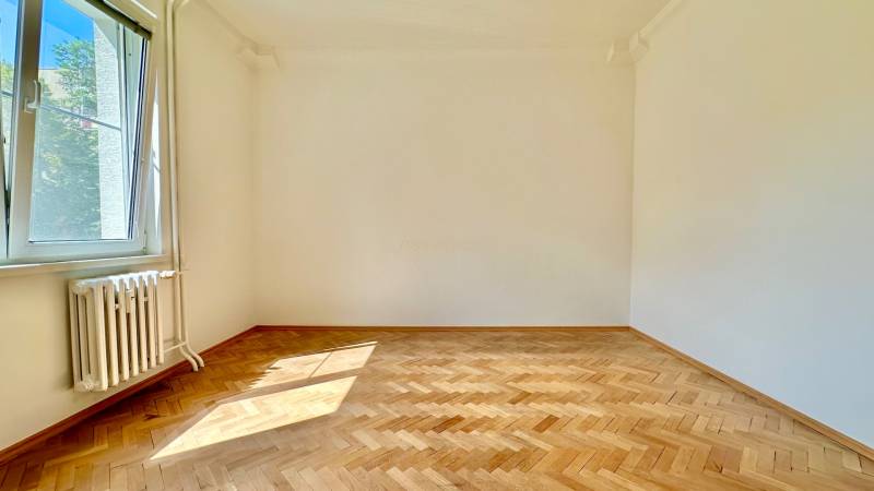 Üres szoba fa padlóval és nagy ablakkal egy háromszobás lakásban.